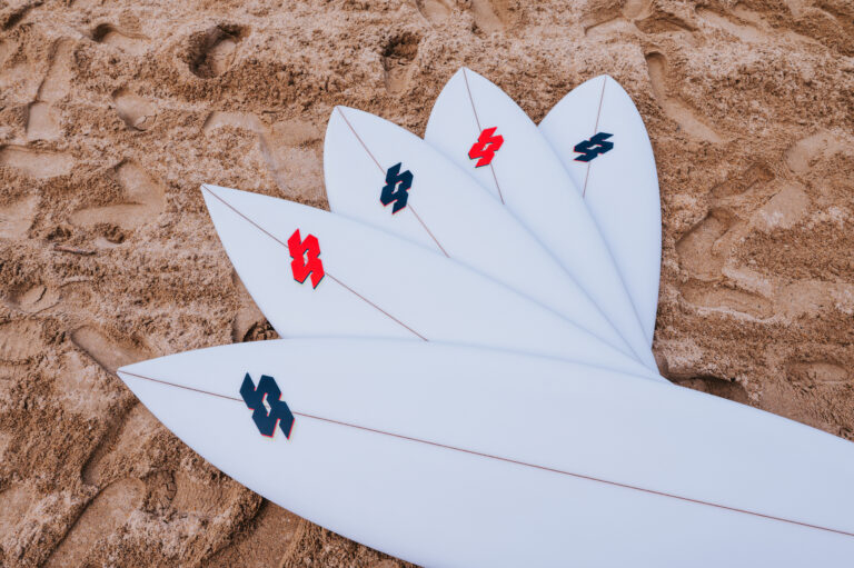 Tablas de surf personalizadas de Secret Shaper en la playa.