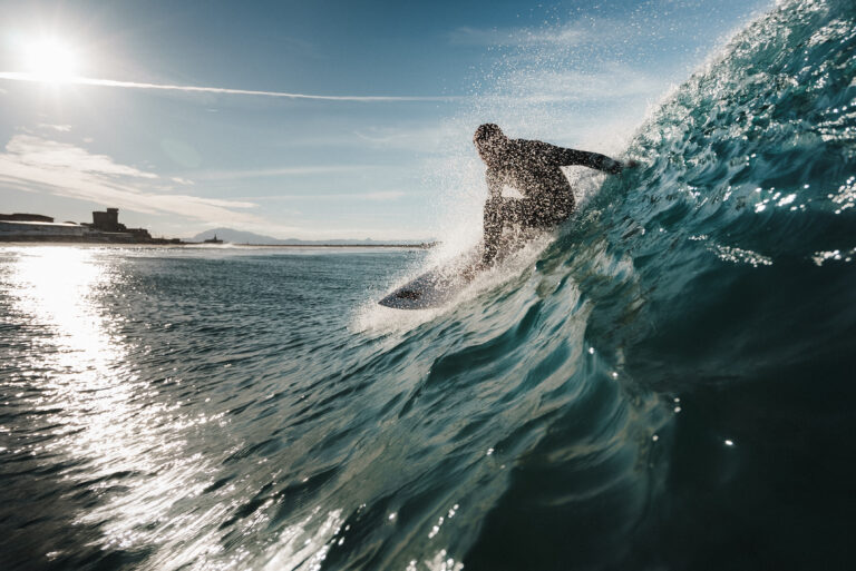 El momento perfecto cuando un surfista realiza un giro sobre una ola mientras el sol brilla detrás de él.